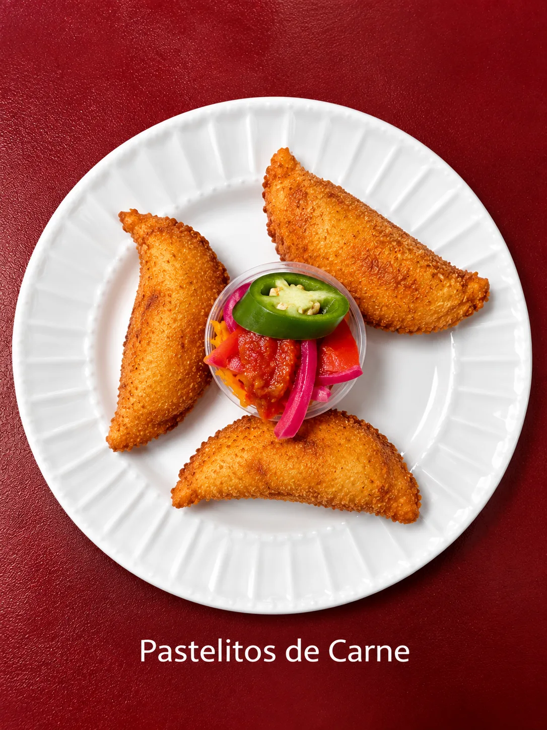 Pastelitos de carne fritos rellenos de carne, servidos con curtido y salsa.