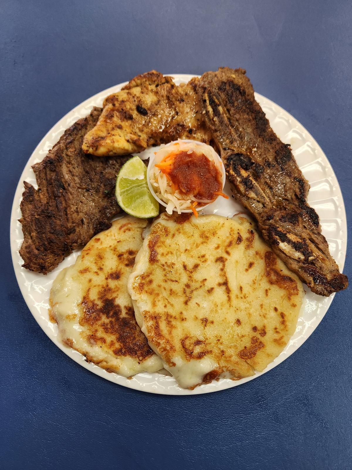 Plato Salvadoreño con pupusas, carne asada, pollo y curtido