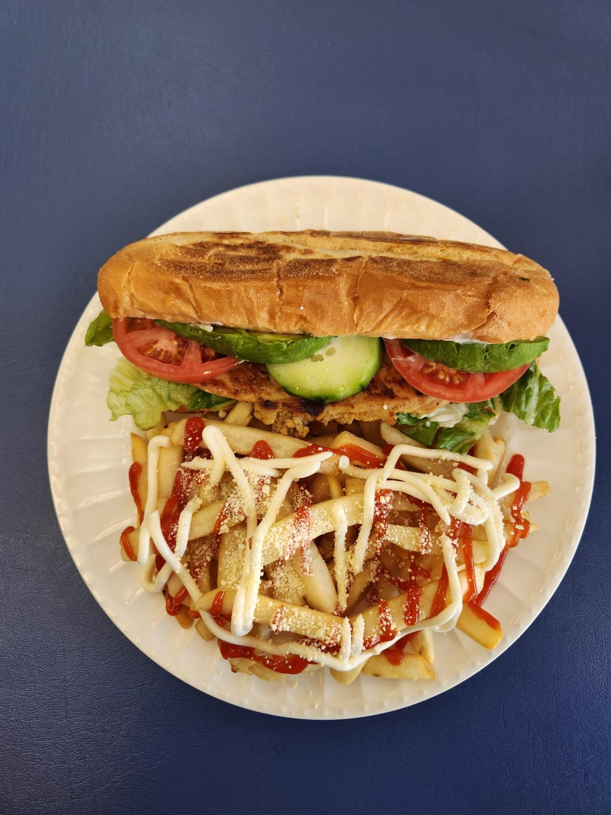 Sándwich de pechuga de pollo con lechuga, tomate, aguacate y papas fritas